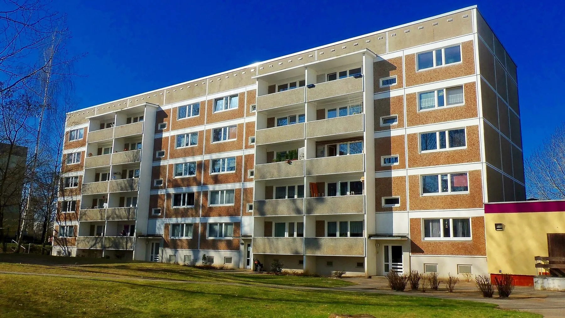 Six-storey residential apartment block under a blue sky