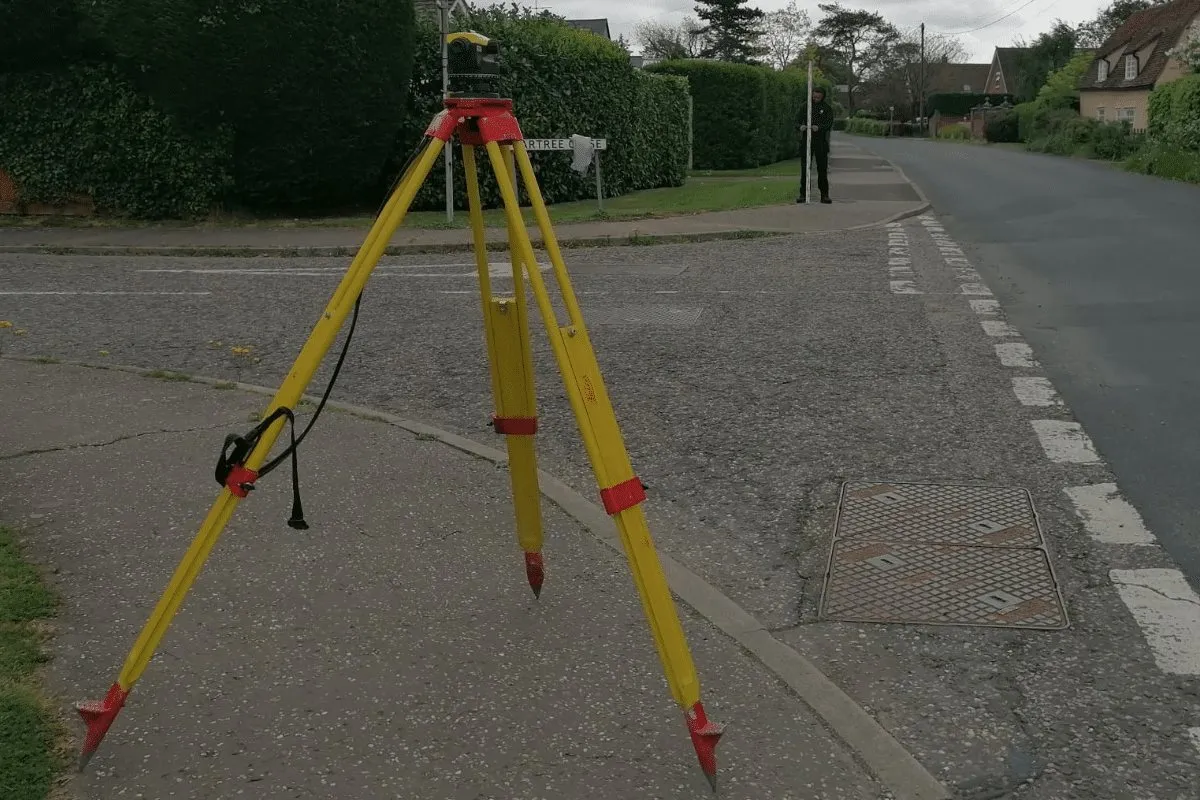 dumpy level on tripod legs next to road