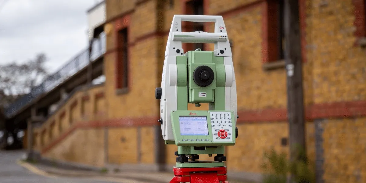 A total station being used next to a wall.